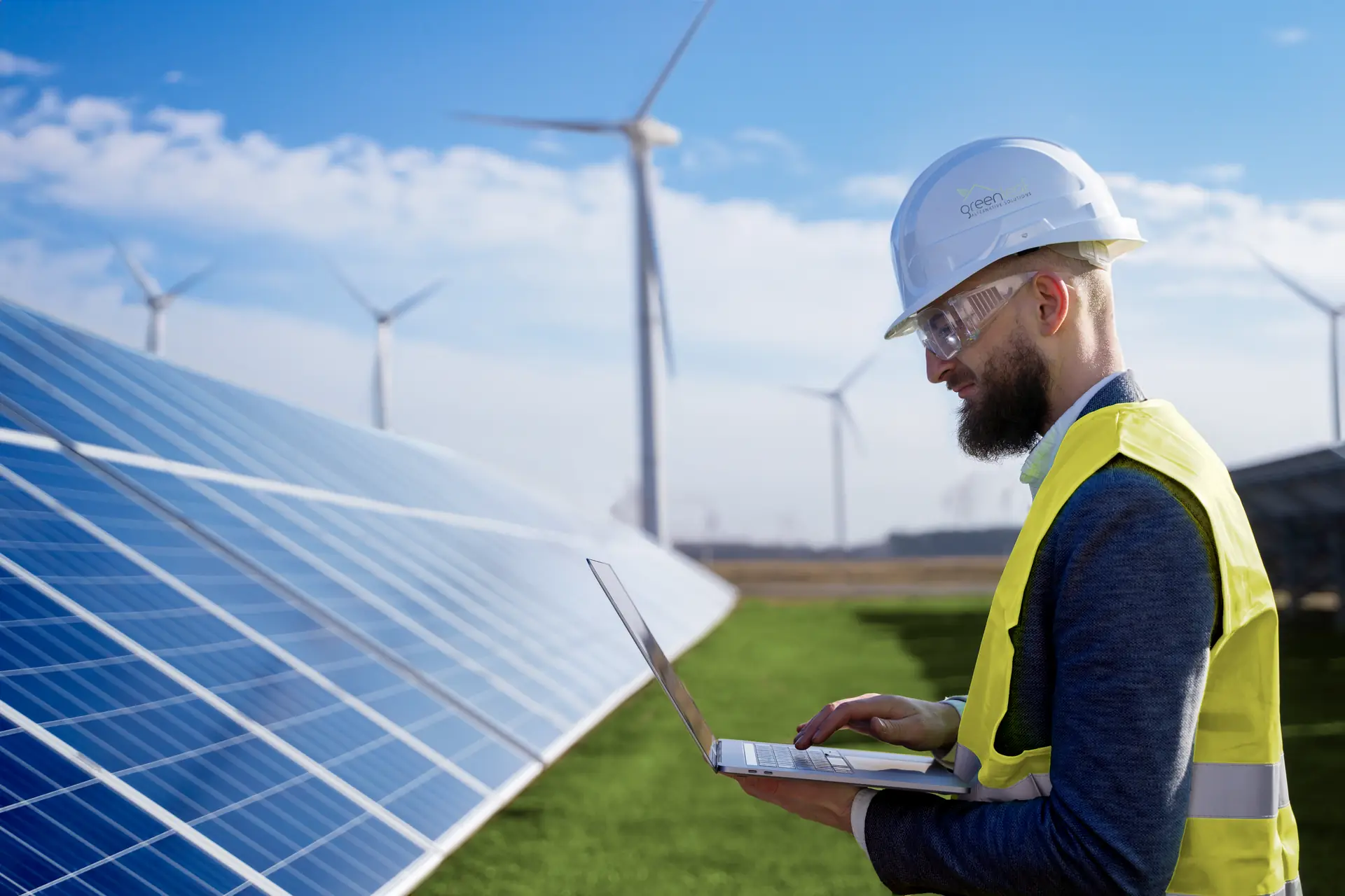 Engineer with a laptop beside a ground-mounted solar array
